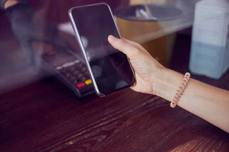 Close-up shot of a hand with a scrunchy of young female holding a smartphone