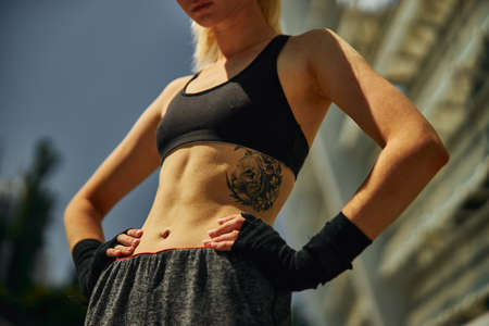 Cropped image of sport belly sportive young woman with black hand wraps for boxing gloves outdoorの写真素材