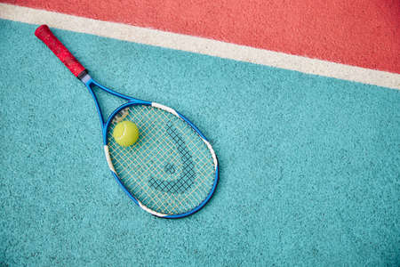 tennis racket with ball outdoors on a color field