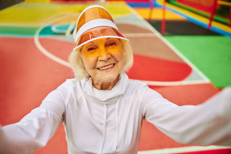 Old, healthy and cheerful lady on a colorfull square outdoors