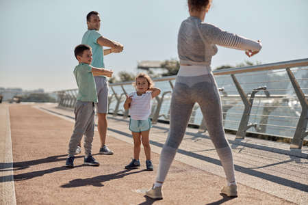 happy healthy and sporty family are doing workout trainings in sunny dayの写真素材