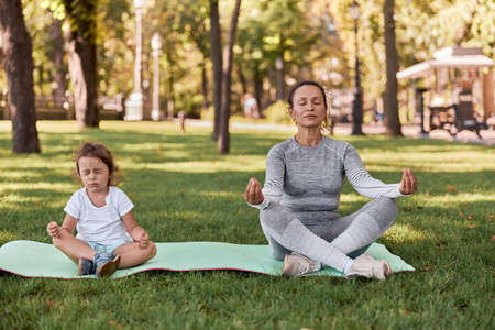 happy healthy and sporty mom and daughter are doing workout trainings in sunny dayの写真素材
