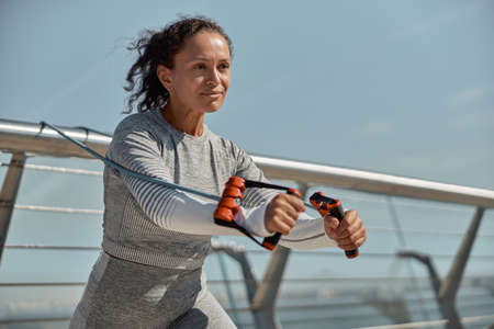 happy healthy and sporty woman is doing harness exercises in sunny day