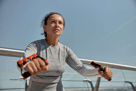 happy healthy and sporty woman is doing harness exercises in sunny day