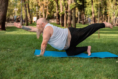 Fat caucasian bearded and bold man is doing morning exercses to loose his weight