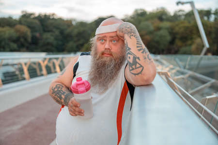 Fat caucasian bearded and bold man is doing morning exercses to loose his weight