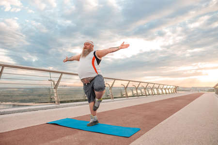 Fat caucasian bearded and bold man is doing morning exercses to loose his weightの写真素材