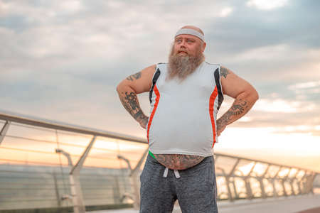 Fat caucasian bearded and bold man is doing morning exercses to loose his weightの写真素材