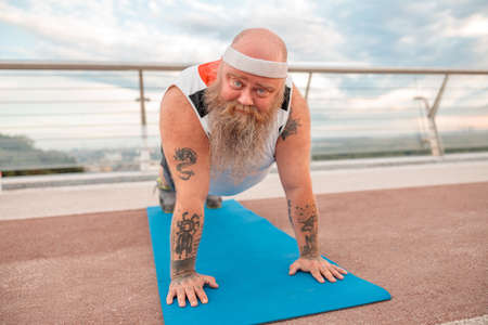 Fat caucasian bearded and bold man is doing morning exercses to loose his weightの写真素材