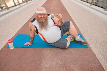 Fat caucasian bearded and bold man is doing morning exercses to loose his weightの写真素材