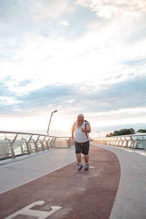 Fat caucasian bearded and bold man is doing morning exercses to loose his weightの写真素材