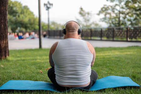 Fat caucasian bearded and bold man is doing morning exercses to loose his weightの写真素材