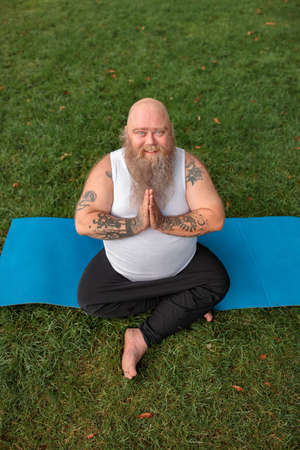 Fat caucasian bearded and bold man is doing morning exercses to loose his weightの写真素材