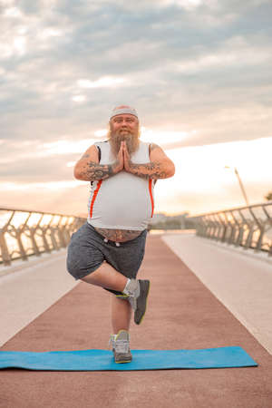 Fat caucasian bearded and bold man is doing morning exercses to loose his weightの写真素材