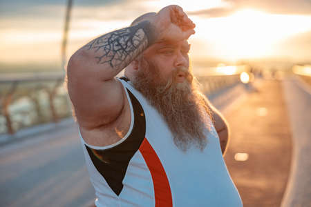 Fat caucasian bearded and bold man is doing morning exercses to loose his weightの写真素材