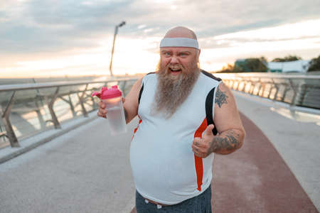 Fat caucasian bearded and bold man is doing morning exercses to loose his weightの写真素材