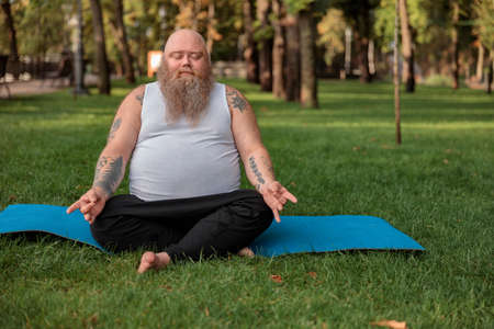 Fat caucasian bearded and bold man is doing morning exercses to loose his weightの写真素材