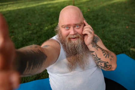Fat caucasian bearded and bold man is doing morning exercses to loose his weightの写真素材