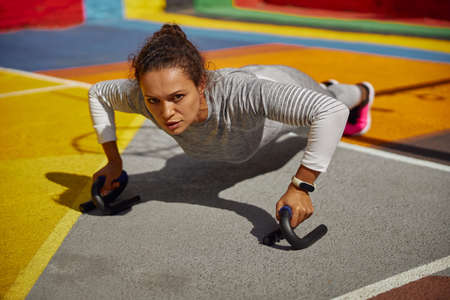 Beautiful healthy cheerful smily woman workout in an urban color city training square