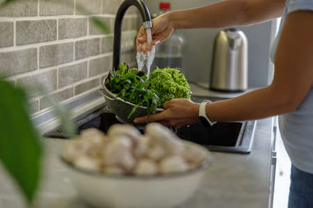 Beautiful smily handsome woman is preparing tasty fresh healthy salad at her kitchen at homeの写真素材