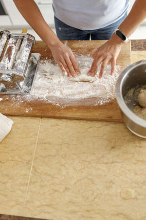 Beautiful smily handsome woman is preparing tasty fresh raw italian pasta at her kitchen at home
