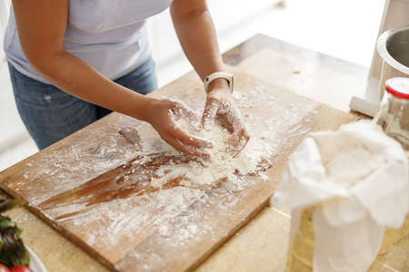 Beautiful smily handsome woman is preparing tasty fresh italian pizzawith vegetables at her kitchen...