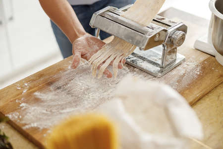 Beautiful smily handsome woman is preparing tasty fresh raw italian pasta at her kitchen at homeの写真素材