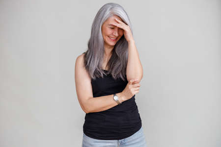 Emotional portraits of a paled long hair asian matured woman on gray background