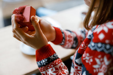 cheerful happy and beautiful caucasian lady is holding a gift in a cozy cafe teraceの写真素材