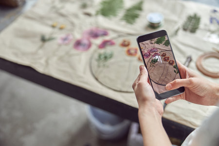 Confident female woman is taking photo on her smartphoneの写真素材