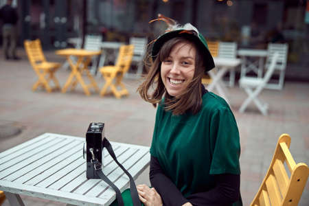 Happy woman in green dress in urban city is sitting near cafeの写真素材