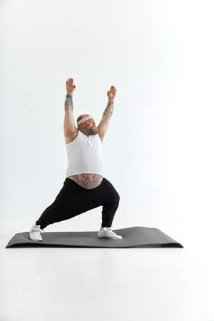 Sporty fat man with beard and tattoos is doing yogaの写真素材