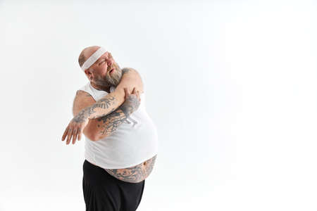 Sporty fat man with beard and tattoos is doing yoga