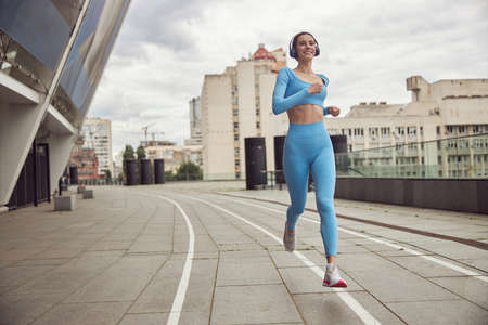 Beautiful fit caucasian woman is doing exercises outdoors at the cityの写真素材