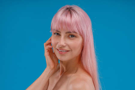 Portrait of beautiful young woman with pink hair and perfect skin smiling at camera, posing isolated...