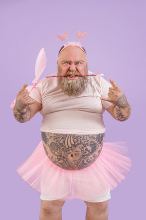 Brutal person in fairy suit shows horns gesture on purple backgroundの写真素材