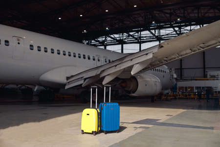 Two colorful suitcases of air stewardesses in empty airport hangar on a sunny day