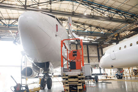 Modern passenger airplane on maintenance repair check in airport hangar indoors