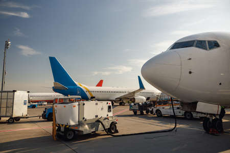 View of white airplane during refueling at airport outdoors on a daytime. Aircraft details