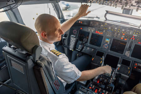 High angle view of professional pilot sitting in an airplane cabin, ready for takeoffの写真素材