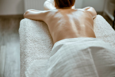 beautiful slim caucasian woman is relaxing on therapist table in spa salonの写真素材