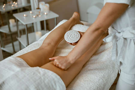 Confident female specialist is doing anticellulite leg massage to beautiful healthy caucasian female clientの写真素材
