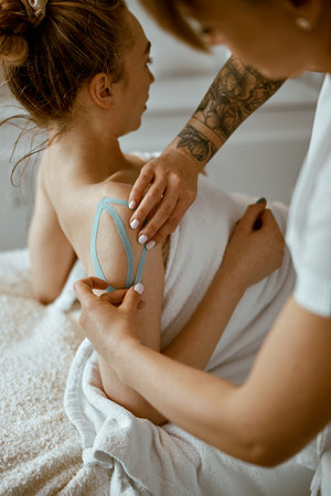 Confident female doctor is doing taping procedure in modenr treatment cabinetの写真素材