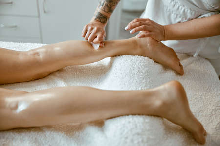 Massagist woman is doing professional leg massage in modern salonの写真素材
