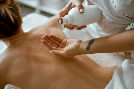 confident female specialist is doing relaxing body massage for beautyful slim caucasian lady at minimalistic spa salonの写真素材