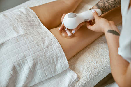 Confident female specialist is doing anticellulite leg massage to beautiful healthy caucasian female...
