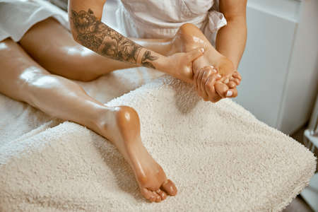 Professional caucasian specialist is doing leg message at modern minimalistic salon