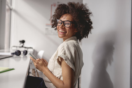 Afro American businesswoman looking at camera while using phoneの写真素材