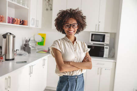 Smiling young lady in glasses posing on coworking kitchen