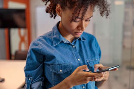 Afro American female employer chatting while texting on phone